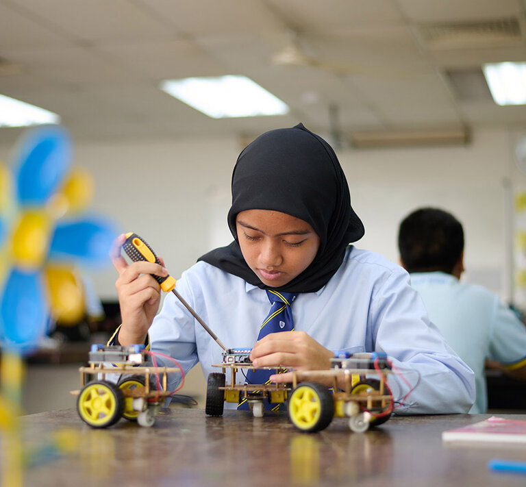 Student fixing an electronical device with a screwdriver