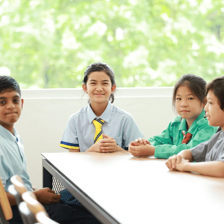 Students sitting at a table and looking at the camera