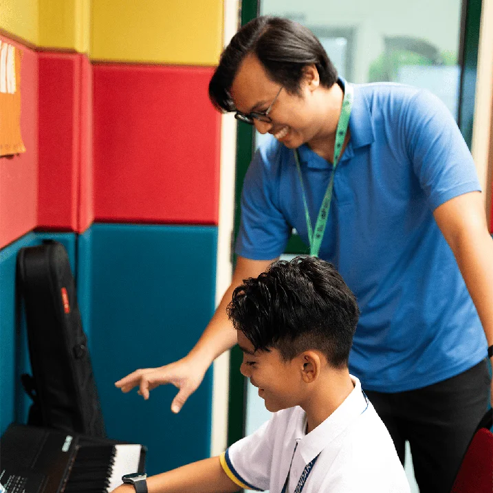 APS student playing piano with his teacher