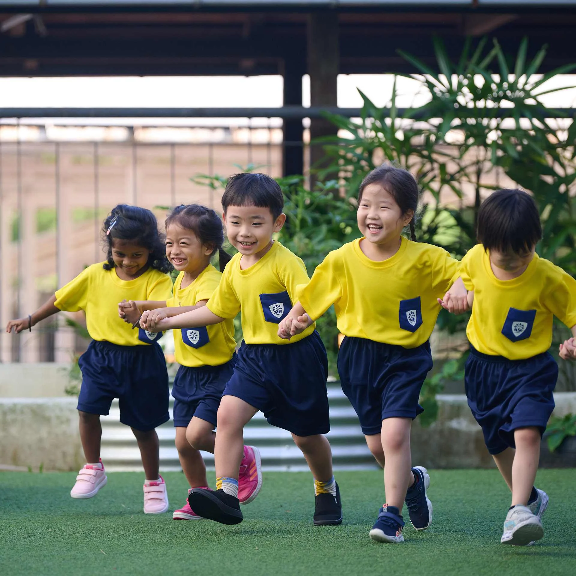 Children running and laughing while holding their hands