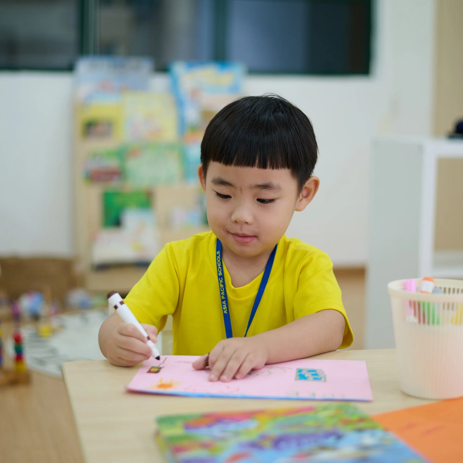 Preschool student drawing on a pink sheet
