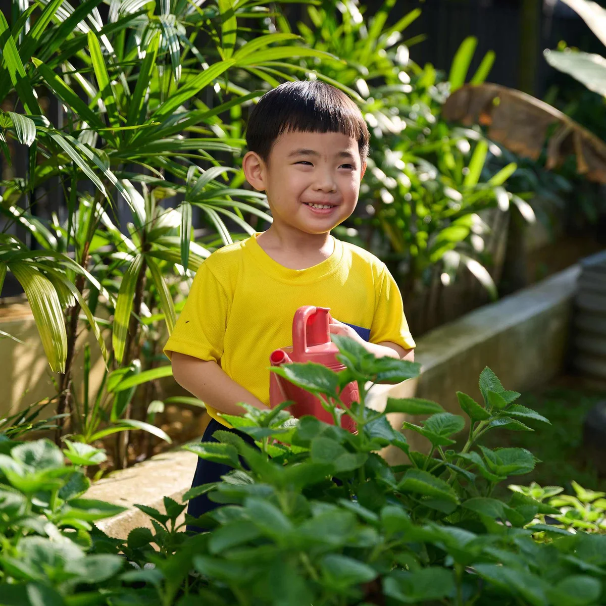 Kid smiling while watering plants