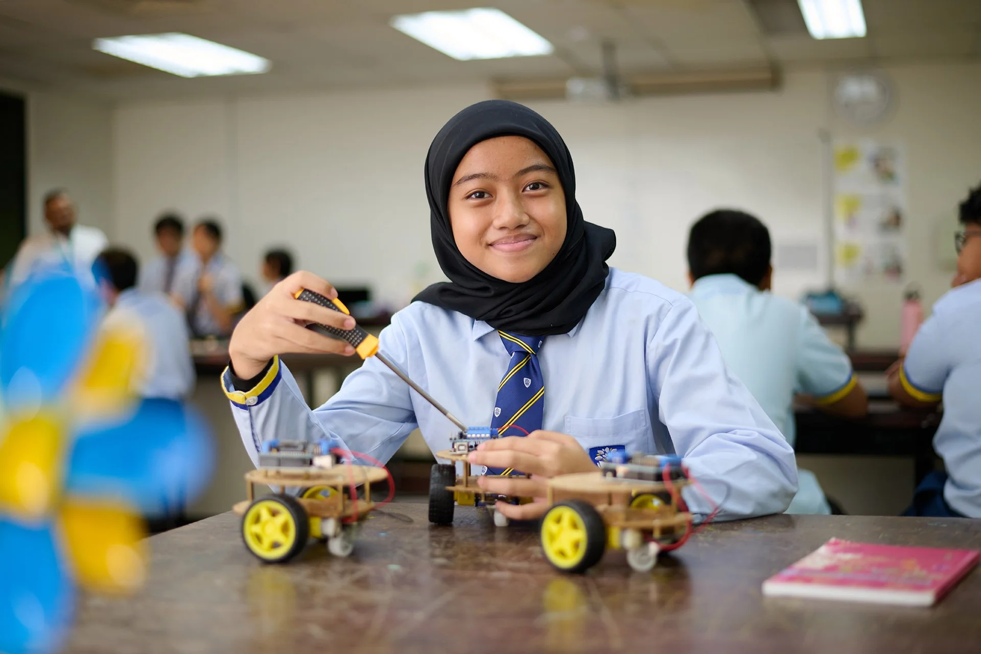 Student smiling while fixing an electronical device