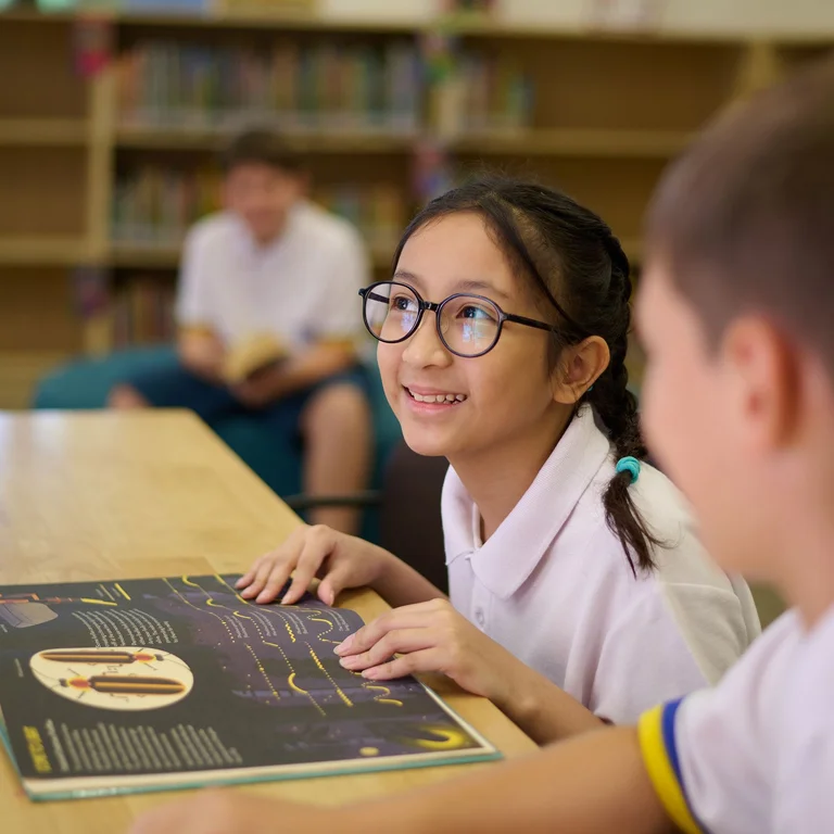 Girl smiling with her hands on a schol desk