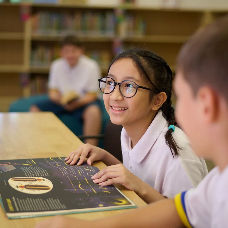 Girl smiling with her hands on a schol desk